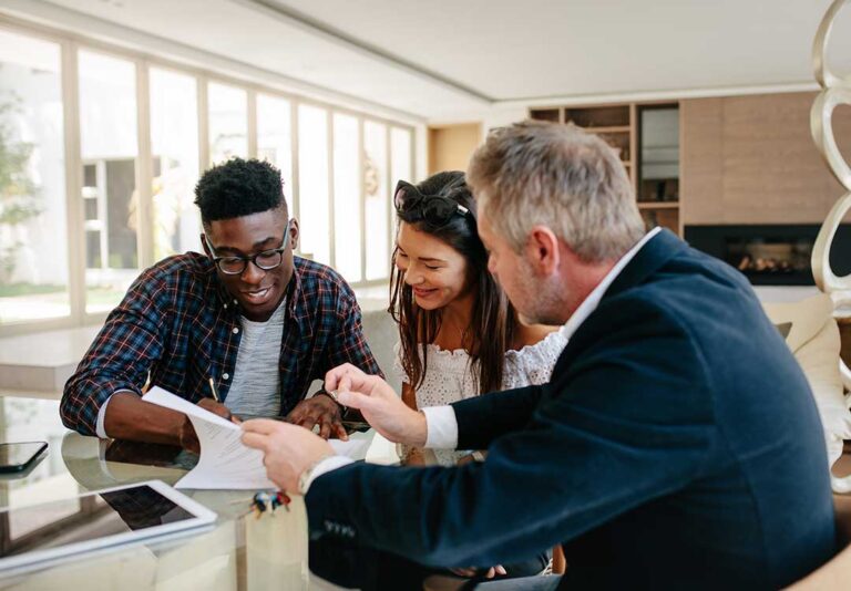 A family sitting at a kitchen table reading through insurance documents together.